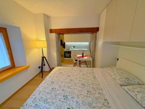 Un pequeño dormitorio con una cama y una cocina. en Casa Colibrì - a few steps from the ski slopes, en Forni di Sopra