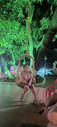 a woman sitting on a swing in a park at Shantadurga Beachside Homestay in Guhagar