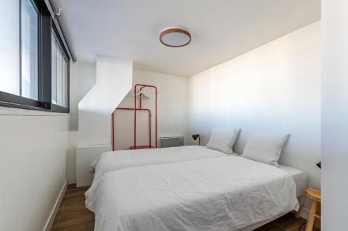 a white bedroom with a white bed and a window at L'Escapade Paris in Le Kremlin-Bicêtre