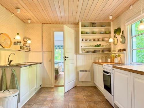 a kitchen with white cabinets and a window at Charming little Swedish cottage in the Big Woods in Svängsta