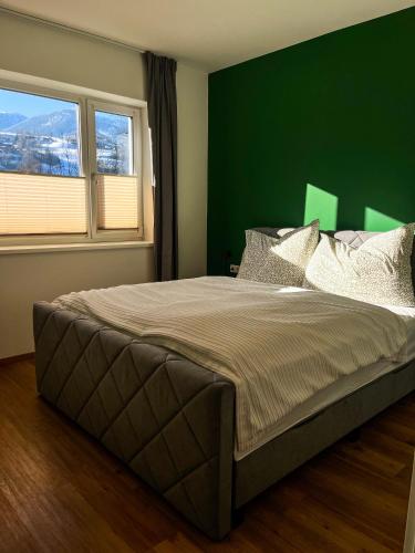 a bedroom with a large bed with a green wall at Bestezeit Appartements in Schladming