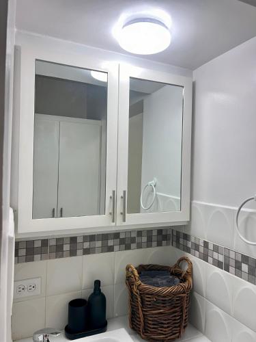 a bathroom with a sink with a mirror and a basket at Estudio acogedor en zona costera in Ensenada