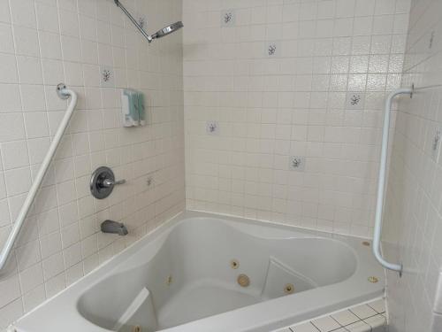 a white bath tub in a white tiled bathroom at Cinderella Motel in Hollister