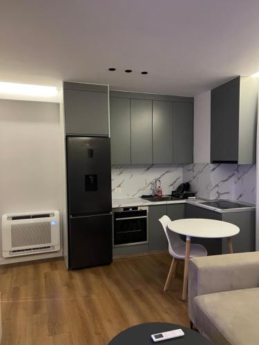 una cucina con un frigorifero nero e un tavolo di Renas apartment 2 a Tirana