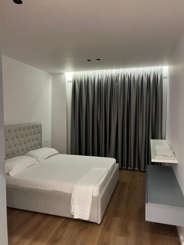 ティラナにあるRenas apartmentのベッドと窓のある白い寝室