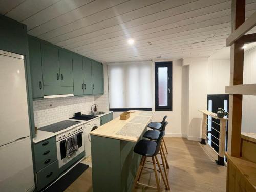 a kitchen with green cabinets and a counter with stools at Casa Arroio - Casco antiguo de Allariz in Allariz