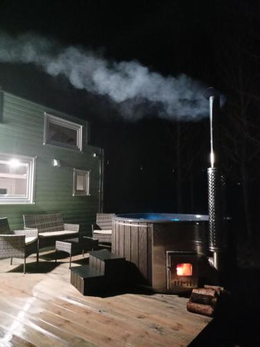 a stage with a fireplace with chairs and a table at Tiny house in the forest in Szlachta