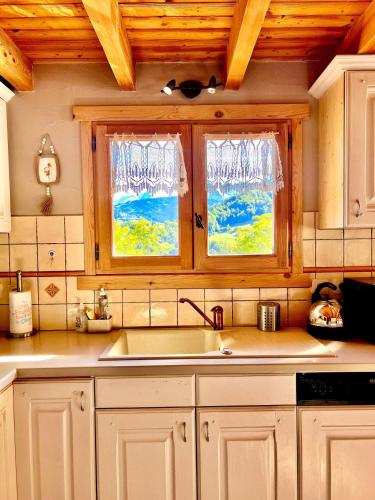 - une cuisine avec des placards blancs, un évier et 2 fenêtres dans l'établissement Charming family Chalet for 8 people, with private Hot Tub, à Les Clefs