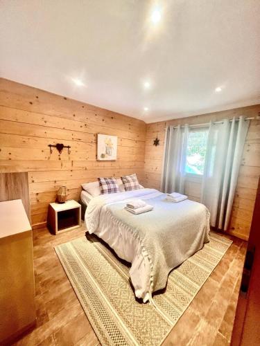 - une chambre avec un grand lit dans un mur en bois dans l'établissement Charming family Chalet for 8 people, with private Hot Tub, à Les Clefs