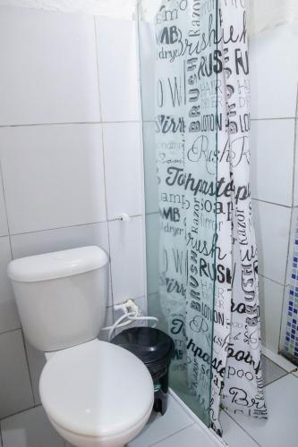 a bathroom with a toilet and a shower curtain at Casa Recife Pousada in Recife