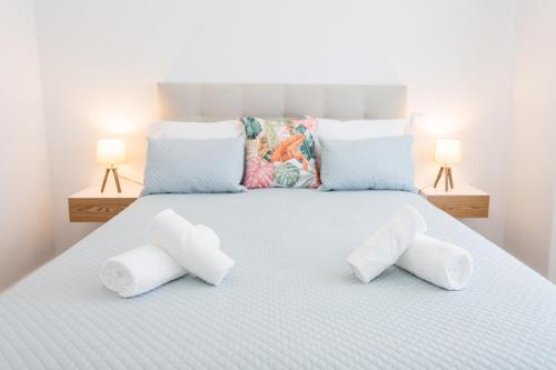 a white bed with four pillows on it with two lamps at Casa da Colina in Ferragudo