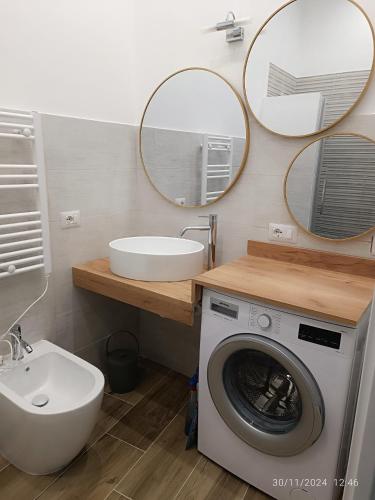 a bathroom with a washing machine and a sink and mirrors at Villanova 48 in Naples