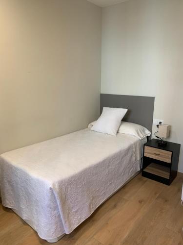 a bedroom with a white bed with a night stand at Cardona Fira in Cardona