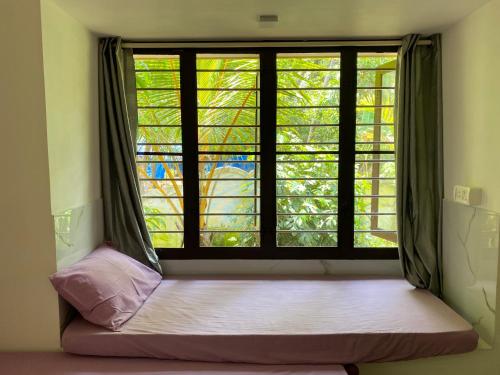 a window in a room with a bed in front of it at Gaya beach hacienda in Irimbranallūr