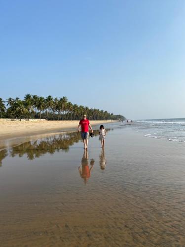 a man and a child walking on the beach at Gaya beach hacienda in Irimbranallūr