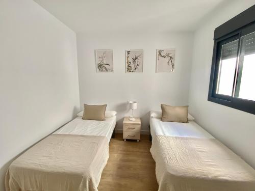 two beds in a room with white walls and a window at Luxury penthouse with pool near Fuengirola beach in Fuengirola