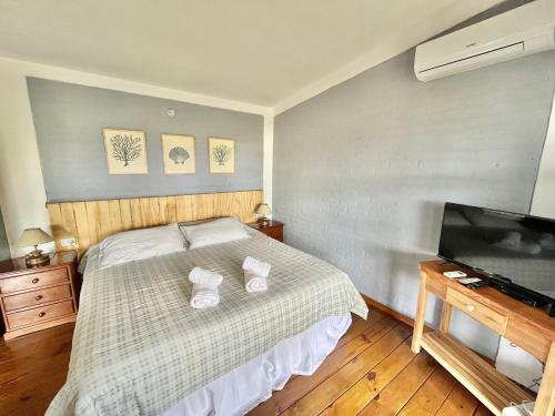 Un dormitorio con una cama con dos almohadas blancas y un televisor. en Je Nous Casa, en José Ignacio
