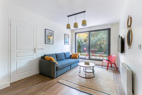a living room with a blue couch and a table at L'Escapade Paris in Le Kremlin-Bicêtre