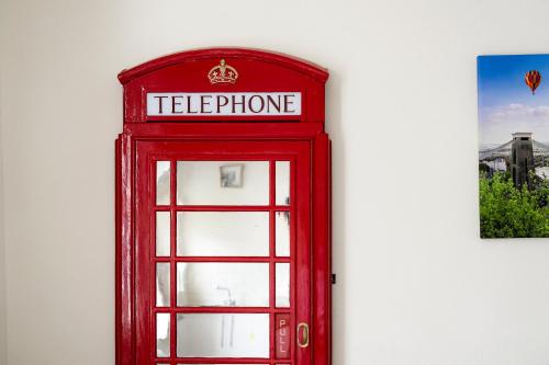 a red phone booth on the side of a wall at STR8BS8 Banksy 2-Bedroom Apartment, Clifton, Parking & Garden in Bristol