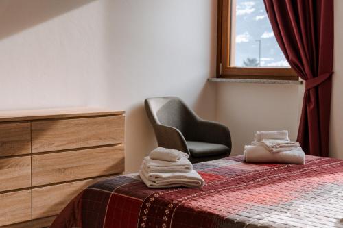 a bedroom with a chair and a bed with a blanket at La Faustina Aosta in Aosta