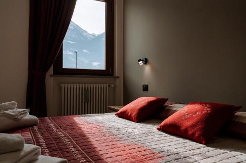 a bedroom with a bed with red pillows and a window at La Faustina Aosta in Aosta