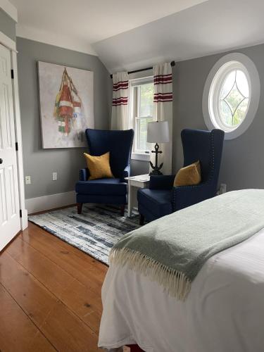a bedroom with two blue chairs and a bed at White Sails Inn in Kennebunk