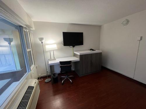 a room with a desk with a computer and a television at The Dylan, a Baymont by Wyndham in Seattle