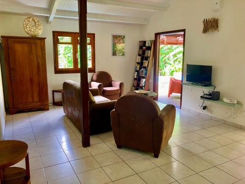 een woonkamer met 2 stoelen en een bank bij Villa Tara Fort Royal in Deshaies
