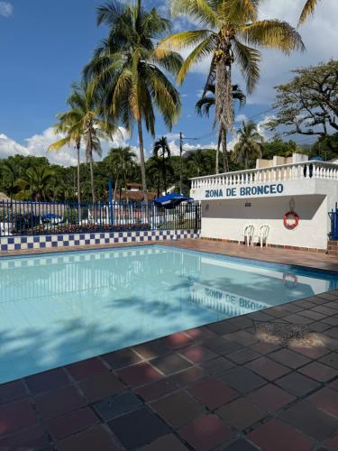 a swimming pool with palm trees in the background at Acogedora cabaña en la Pintada in La Pintada