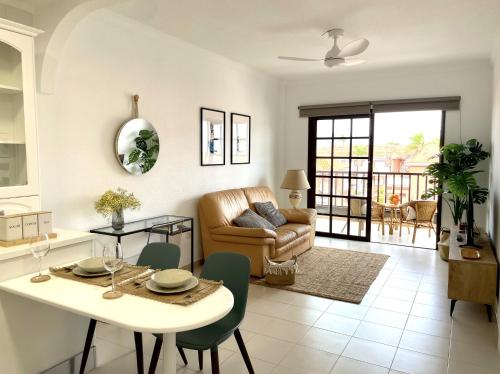 ein Wohnzimmer mit Tisch und Couch in der Unterkunft Apartamento con piscina junto al mar in Arona