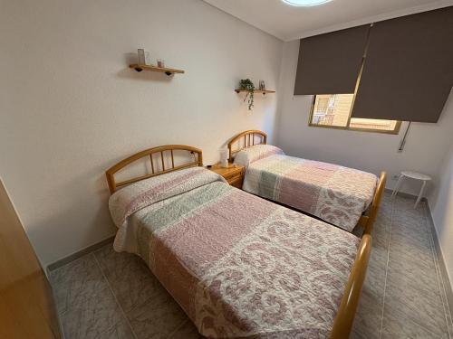 two beds in a small room with a room with a window at Apartamentos La Laguna II in Los Alcázares