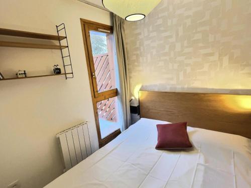 a bedroom with a bed with a red pillow on it at Résidence Hameaux De Val - Appartement accueillant et son parking couvert MAE-5781 in Val dʼIsère