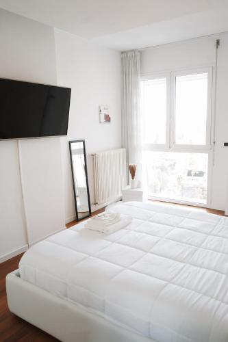 a white bedroom with a large white bed and a flat screen tv at NSH Apart Malpensa in Gallarate
