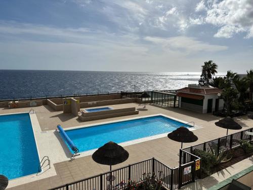 a swimming pool with umbrellas next to the ocean at Atlantic View Tenerife South in Arona