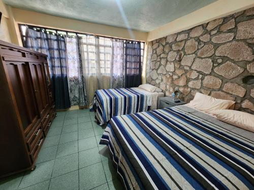 a hotel room with two beds and a stone wall at Casa Gomez in Taxco de Alarcón