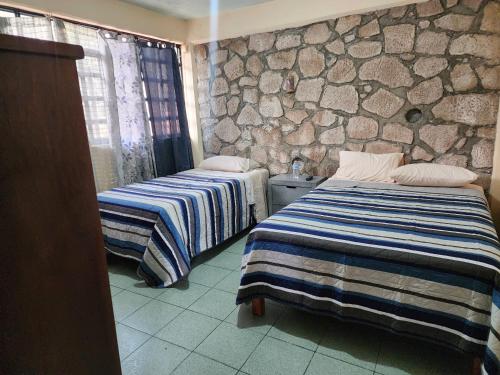 two beds in a room with a stone wall at Casa Gomez in Taxco de Alarcón