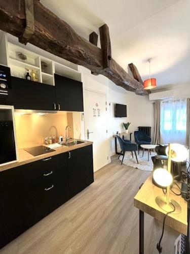 une cuisine avec des armoires noires et un salon dans l'établissement G5 Appartement Climatisé Centre Angouleme, à Angoulême
