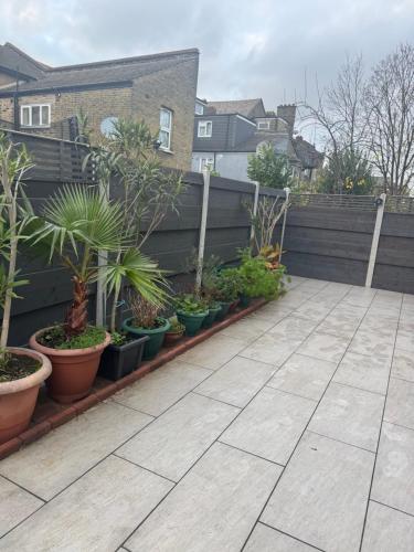 a garden with plants in pots on a fence at Modern House Apartment Stratford E15 London - Sleeps 2 - 9, Fast Links to Central London, Near O2, Greenwich & Olympic Park, Child-Friendly Garden, Free Parking, Free WiFi in London