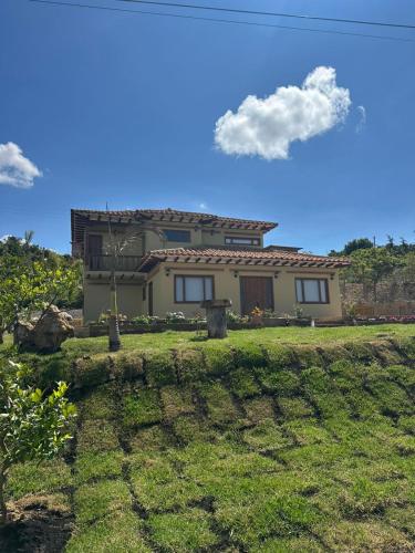 a house on a hill with a grass yard at Hotel Sol de la Montaña Villa de leyva in Villa de Leyva