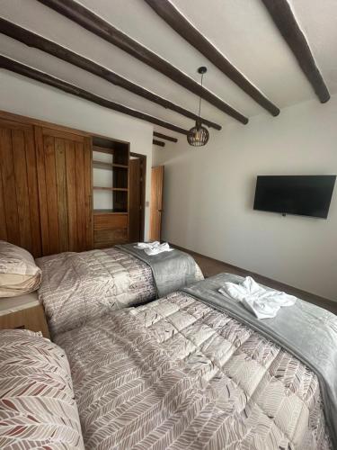 a bedroom with two beds and a flat screen tv at Hotel Sol de la Montaña Villa de leyva in Villa de Leyva