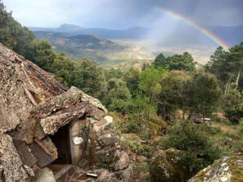 a rainbow over an old stone house with a mountain at Rifugio Ortobene in Nuoro