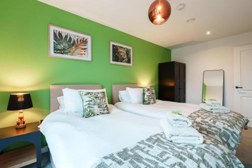 two beds in a room with green walls at Jungle Luxe Retreat, 2Bed 2Bath Leeds, Center & Stadium in Leeds