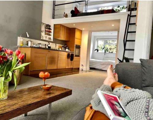 a person sitting on a couch in a living room at Lovely New York style flat in Greenwich - Blackheath in London