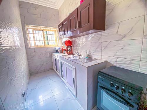 a white kitchen with a sink and a stove at Résidence Raffinée-Pour une expérience unique in Cotonou