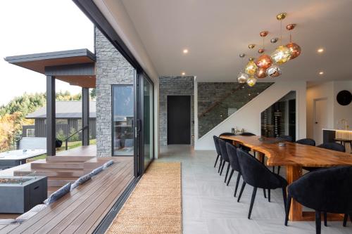 a dining room with a long wooden table and black chairs at Aroha on Florence by Sothebys Luxury Rental Homes in Queenstown