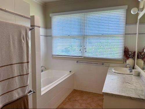 a bathroom with a bath tub and a sink at Ulmarra in Sussex inlet