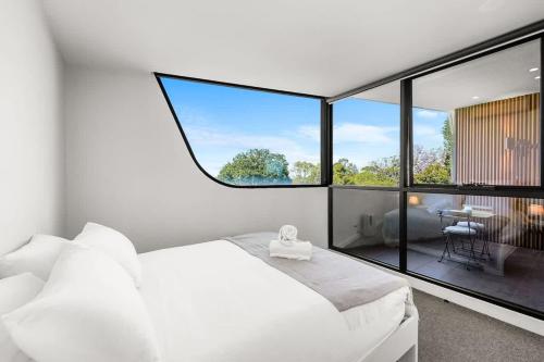 a bedroom with a white bed and a large window at Perfectly Located Executive 1BR at Caulfield North in Melbourne