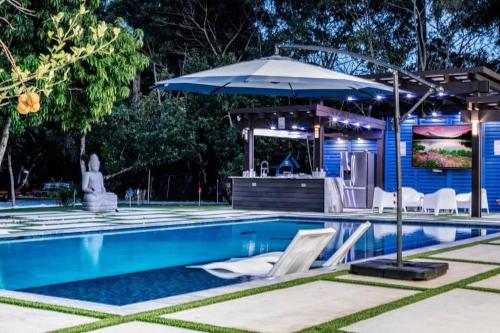 a swimming pool with an umbrella and a house at Lake Of Dreams Miami House in Miami