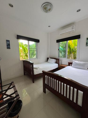 a bedroom with two beds and two windows at Relax private Pool Villas - 4 bedroom villas in Ao Nang Beach