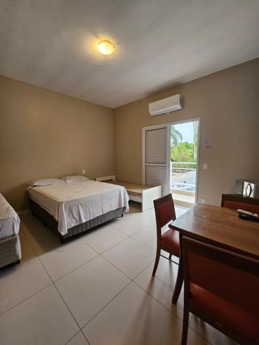 a bedroom with a bed and a desk and a table at Suíte privativa proxima ao Sesc 2 in Bertioga